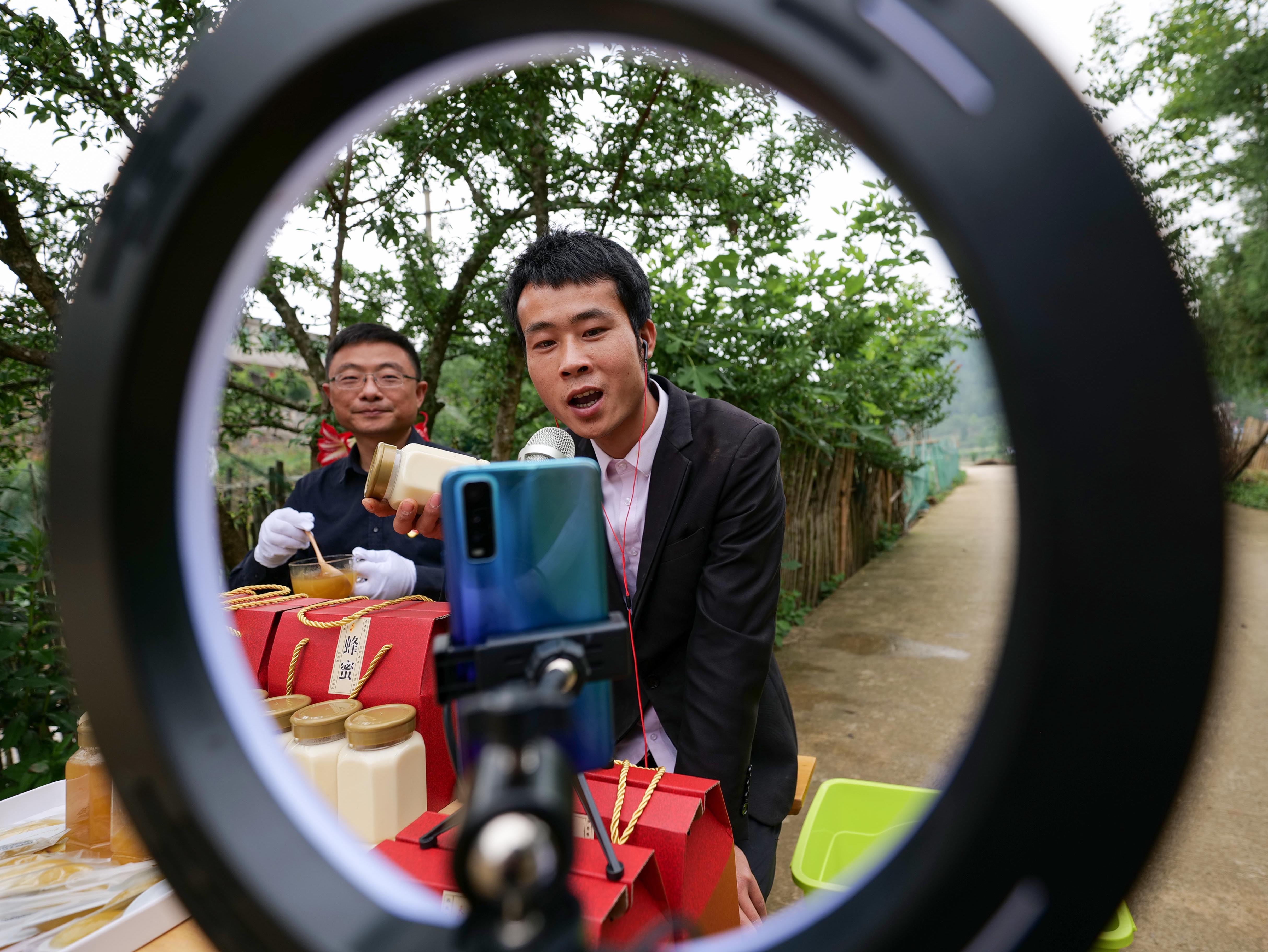 2022年5月13日，在贵州省黔东南苗族侗族自治州岑巩县羊桥土家族乡坪地村，驻村第一书记万伦宇（左）帮助村民在互联网上销售蜂蜜。杨云 罗慧 任元摄 (3).JPG