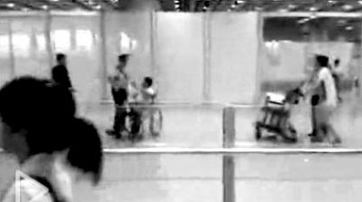 爆炸前2秒，安保人员协助推车的白衣旅客(右)撤离。