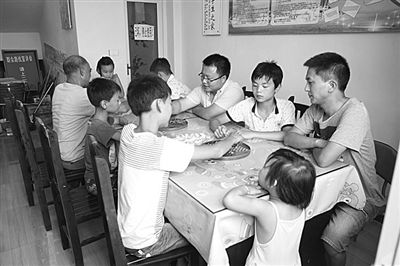 8月4日，在四川省广安市广安区大龙乡果坝村留守儿童托管所，大学生村官彭钒右一与党员志愿者在与留守儿童下棋，让留守儿童欢乐过暑假。